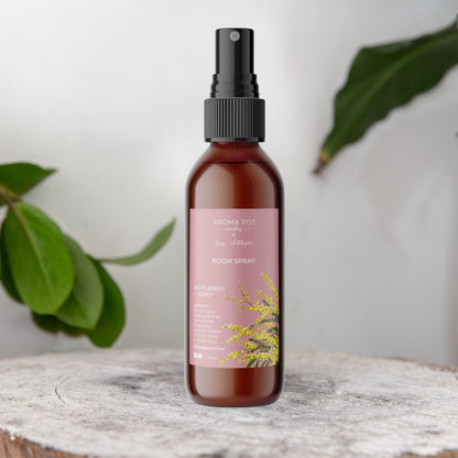 Amber Bottle Room spray with Pink label showing our new wattle artwork and wattleseed and honey scent on label
